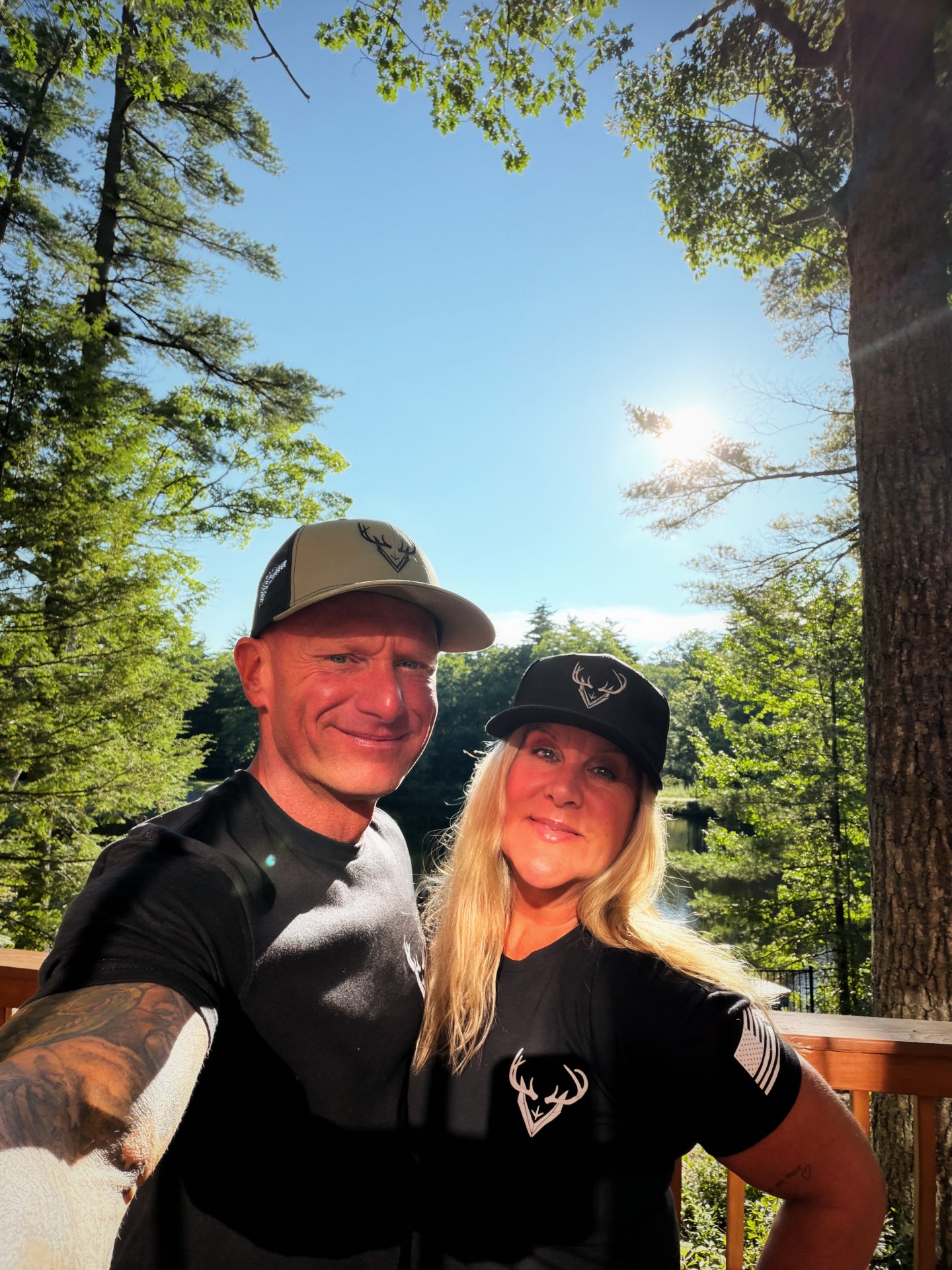 Anthony DelVecchio and his wife in DelVecchio Outdoors caps and tees by the water