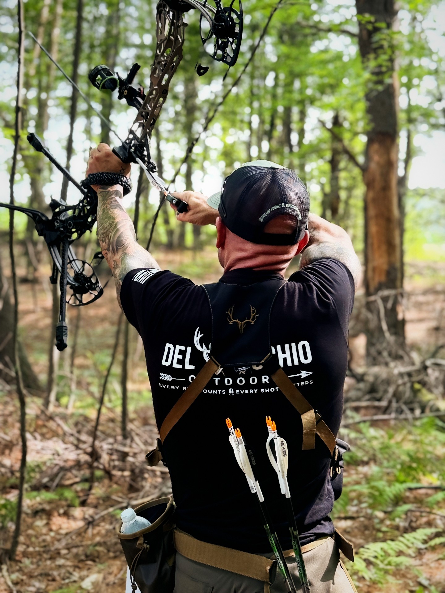 Anthony DelVecchio drawing his bow skyward in a DelVecchio Outdoors shirt