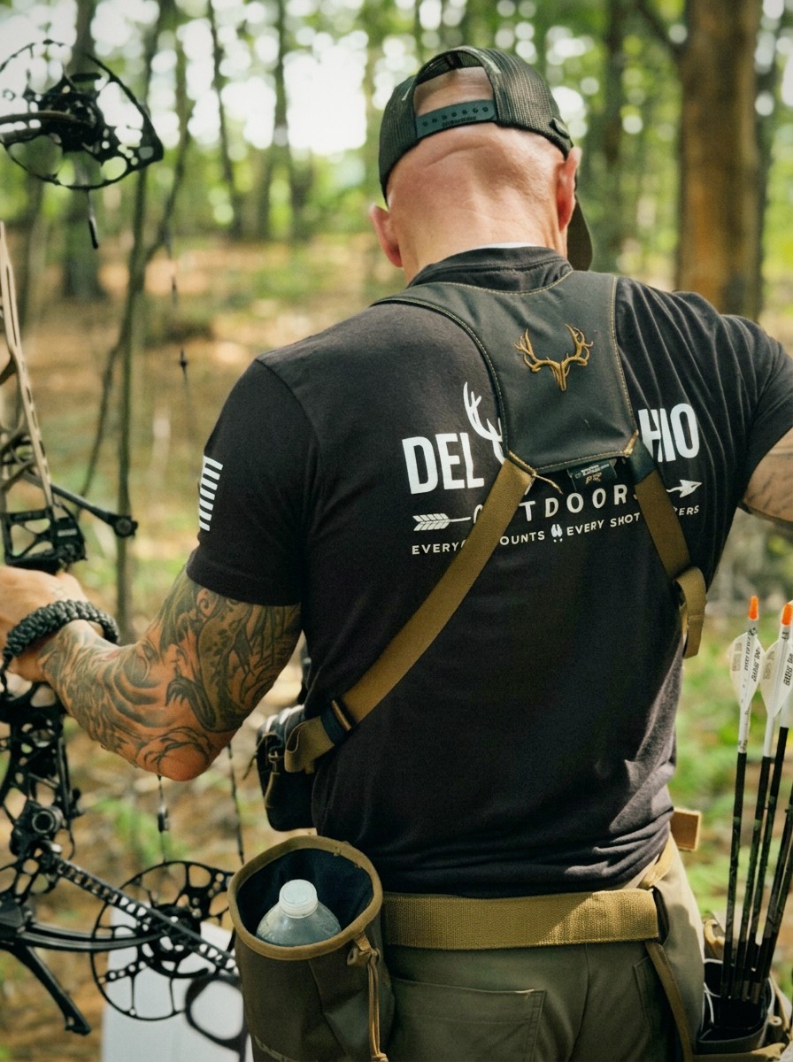 Anthony DelVecchio carrying a compound bow and wearing DelVecchio Outdoors gear